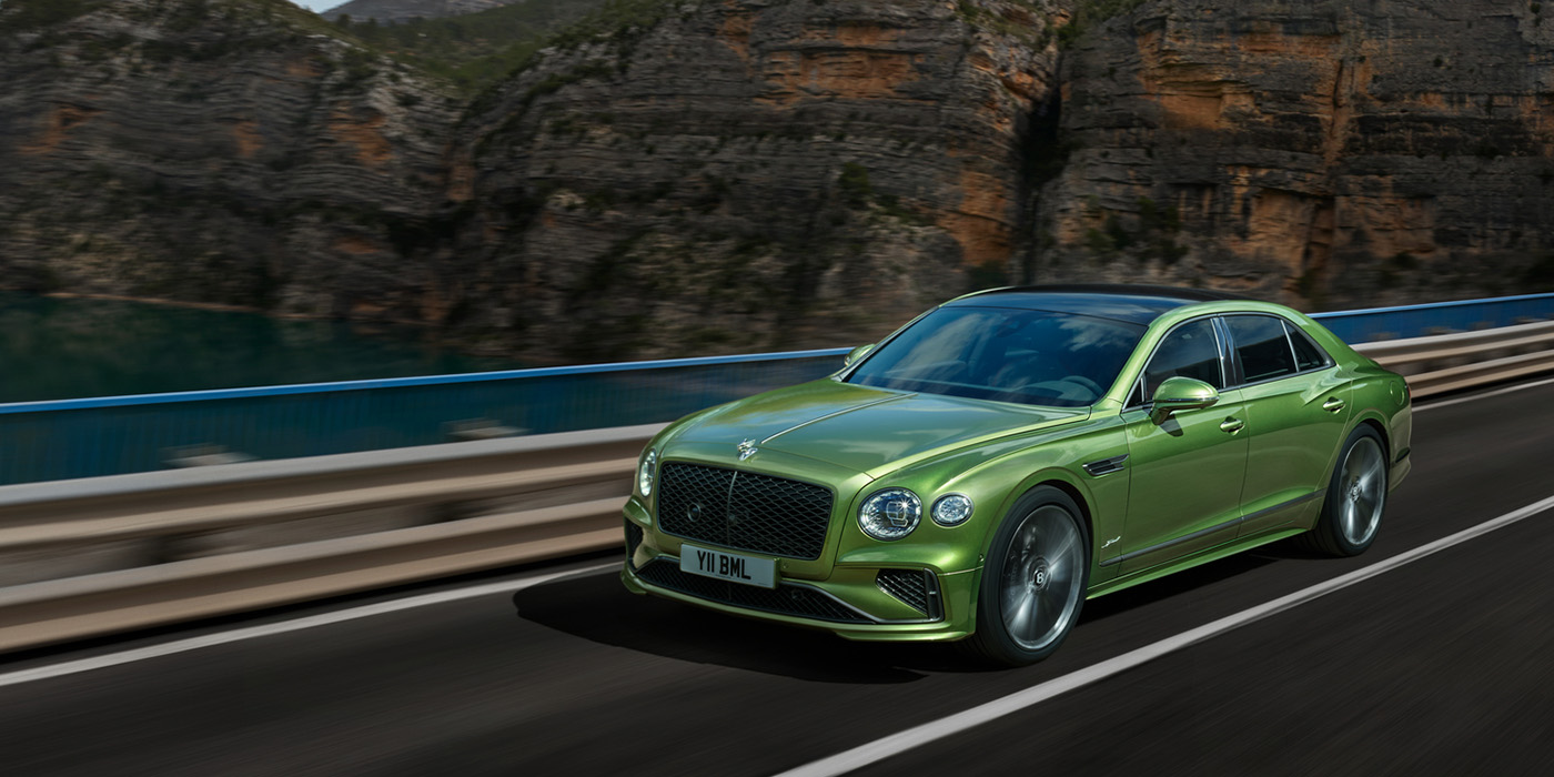 Bentley Berlin Bentley New Flying Spur Speed v8 hybrid sedan driving dynamically on a mountain road in Tourmaline Green paint