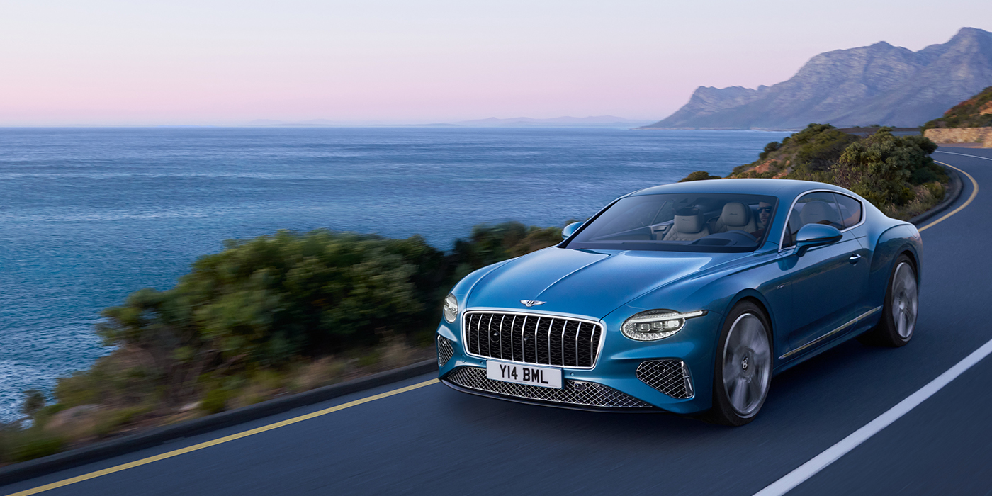 Bentley Berlin New Bentley Continental GT Azure coupe in Light Windsor blue paint with 22 inch Azure wheels and chrome grill, driving dynamically by the sea