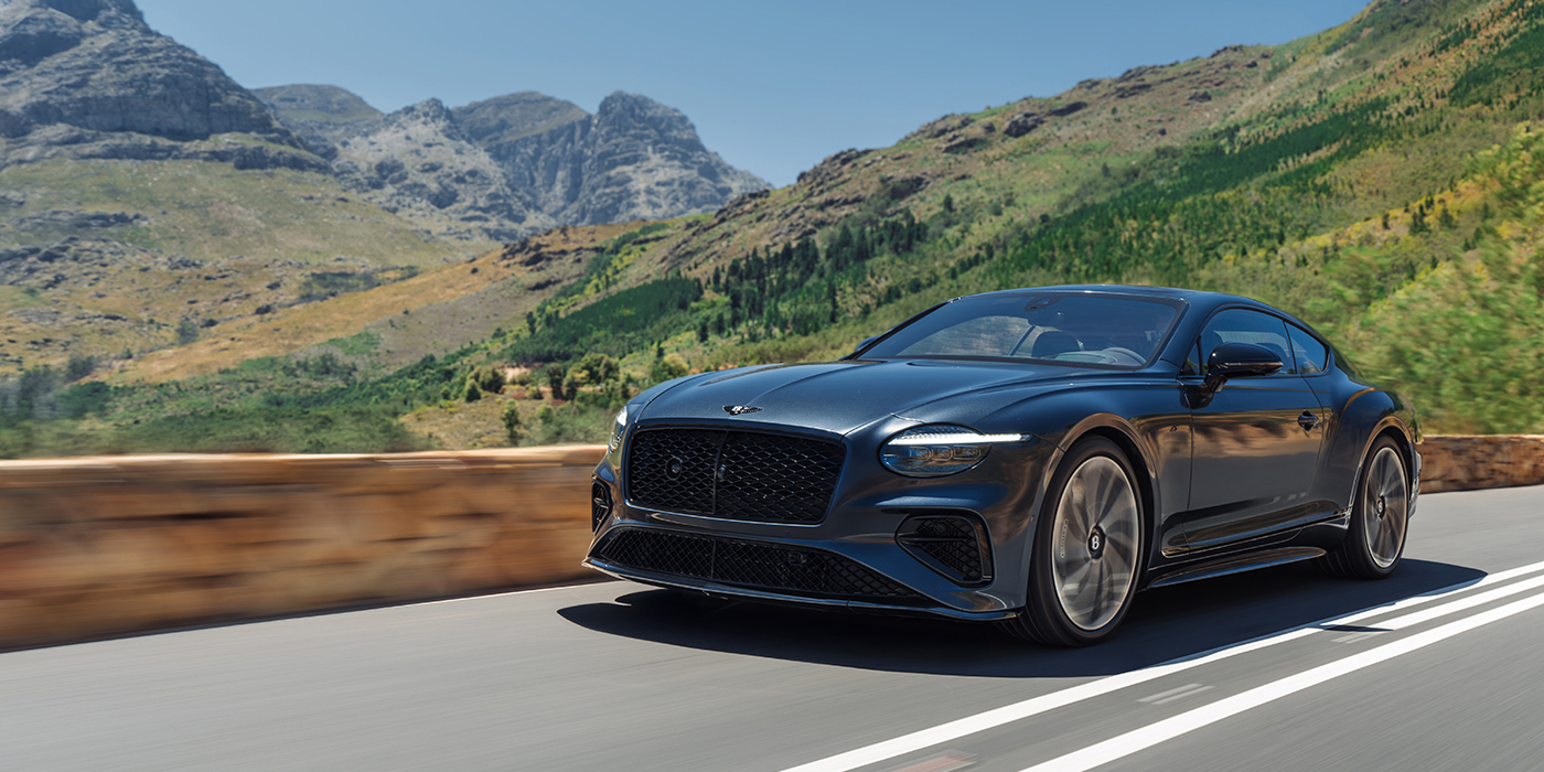 Bentley Berlin Bentley Continental GT coupe in Thunder paint and 22" ten swept spoke wheels front 3/4 driving on mountain road