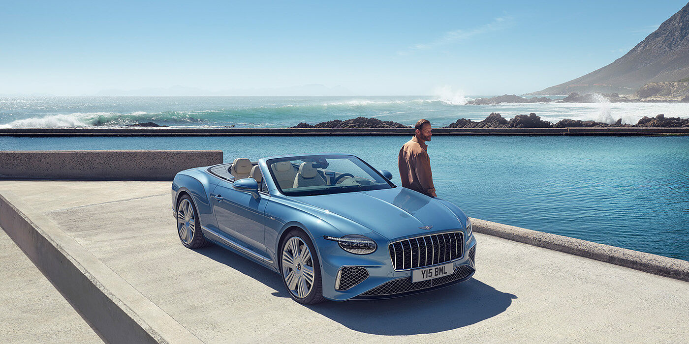 Bentley Berlin New Bentley Continental GTC Azure convertible front view in Light Windsor blue paint with 22 inch ten spoke wheels parked by the sea in the sunshine