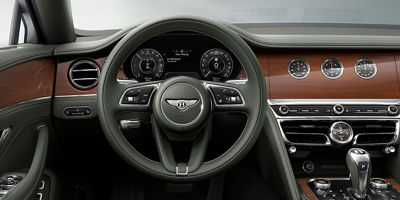 Bentley Berlin New Bentley Flying Spur sedan front cabin in Cumbrian Green hide and Crown Cut walnut veneer showing steering wheel and Rotating Display with three clocks on face