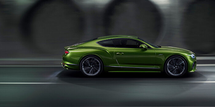  Bentley Berlin Bentley Continental GT coupe in Tourmaline Green paint driving in profile on a dark road